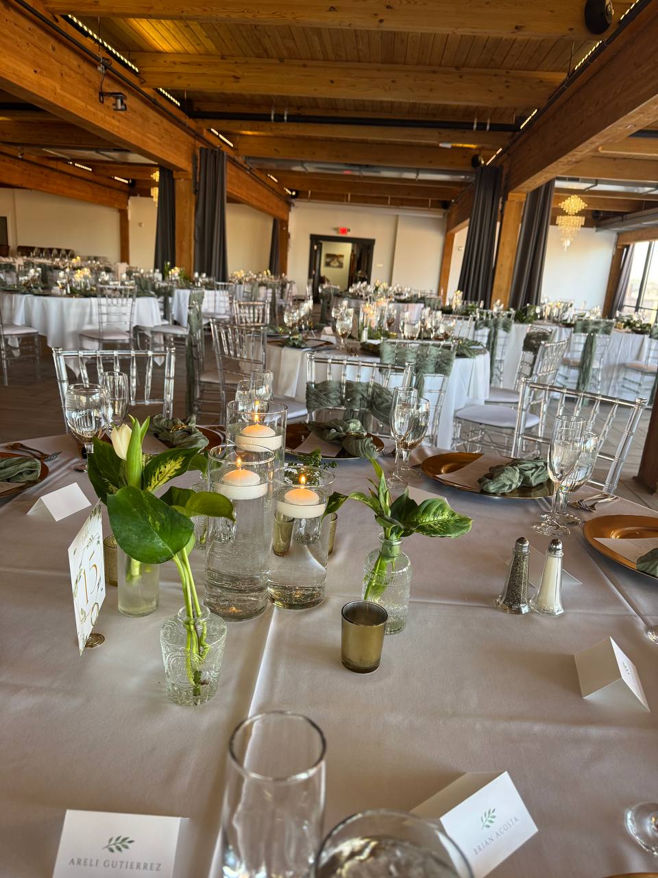 Reception table setting with candles, greenery, and glassware